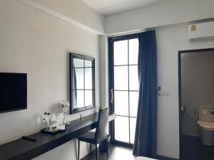 a bathroom with a desk and a toilet and a window at Azz Hotel in Chiang Mai