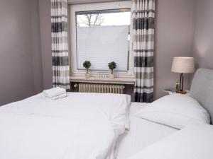 2 weiße Betten in einem Zimmer mit Fenster in der Unterkunft Apartment Langeoog by Interhome in Norddeich