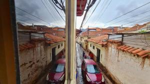 zwei Autos in einer Gasse zwischen zwei Gebäuden geparkt in der Unterkunft QORY WASY in Cusco
