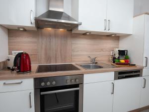 eine Küche mit weißen Schränken und einer Spüle aus Edelstahl in der Unterkunft Holiday Home Sonnenschein by Interhome in Norddeich