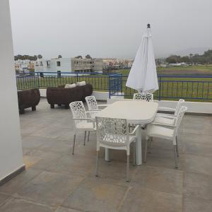 a white table and chairs and an umbrella on a roof at G&E Harbour Apartments in Lachi