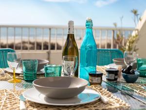 a table with a bottle of wine and glasses at Apartment La Calypso-5 by Interhome in La Grande-Motte