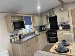 a kitchen with wooden cabinets and a table with dishes on it at Cosy Holiday Home, Home Farm Holiday Park in Brent Knoll