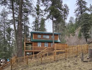a log cabin in the woods with a wooden fence at Sky Cabin in Ruidoso