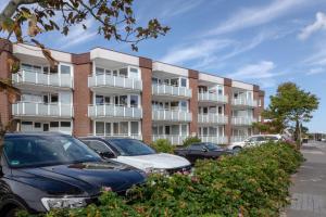 an apartment building with cars parked in front of it at Louis in Westerland (Sylt)