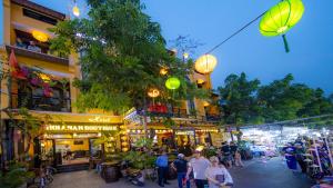 uma multidão de pessoas andando por uma rua em um mercado em Hoianan Boutique Hotel em Hoi An