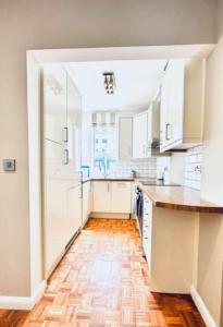 uma cozinha com armários brancos e piso em madeira em Home far from home in central London em Londres