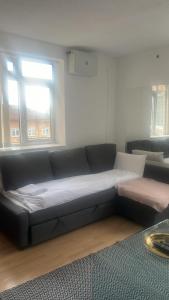 - un canapé noir dans le salon doté d'une fenêtre dans l'établissement Fernando flats, à Londres