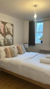 a large white bed in a bedroom with a window at Fernando flats in London