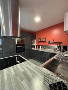 a kitchen with black cabinets and red walls at Rez-de-chaussée de plain-pied avec parking privé au centre ville in Dieppe