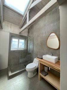 a bathroom with a toilet and a sink and a mirror at Casa La Escondida, Punta Sirena in Pelluhue
