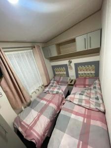 two beds in a small room with a window at Cosy Holiday Home, Home Farm Holiday Park in Brent Knoll