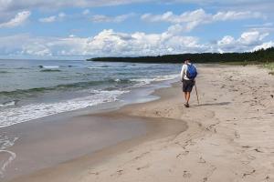 Un hombre con una mochila caminando por la playa en Fantastiskt hus på fårö, en Fårö