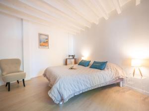 a white bedroom with a bed and a chair at Holiday Home La Belle Tendel by Interhome in Arcachon