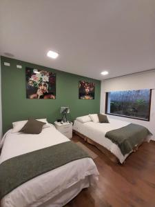 two beds in a bedroom with green walls at 593 Hotel Boutique Baños in Baños