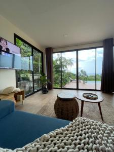a living room with a blue couch and a large window at SEASUN Villa Haad Tien in Haad Tian