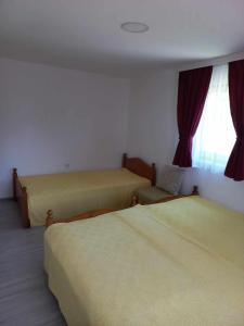 Cette chambre comprend 2 lits et une fenêtre. dans l'établissement Apartman Tošić, à Trnava