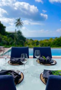 a table with two chairs and wine glasses on it at SEASUN Villa Haad Tien in Haad Tian