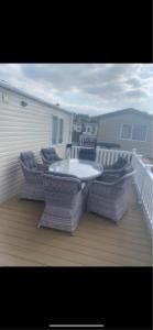 a patio with a table and chairs on a deck at Cosy Holiday Home, Home Farm Holiday Park in Brent Knoll