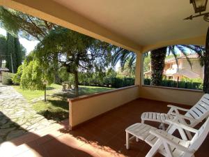 un porche con 2 sillas blancas y un árbol en Holiday Home Siby-3 by Interhome, en Casale Marittimo
