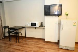 a room with a table and a refrigerator with a tv on top at Bkk39 Airport hotel in Ban Khlong Prawet