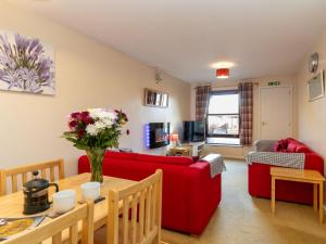 a living room with a red couch and a table at Holiday Home Glenfiddich by Interhome in Aviemore
