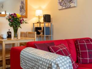 a living room with a red couch and a table at Holiday Home Glenfiddich by Interhome in Aviemore