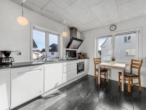 een keuken met witte kasten en een tafel en stoelen bij Holiday Home Ullakarin - 200m from the sea in Western Jutland by Interhome in Thyborøn