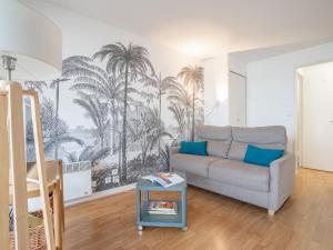 ein Wohnzimmer mit einem Sofa und einem Palmenmilch in der Unterkunft Apartment Aquitania-5 by Interhome in Arcachon