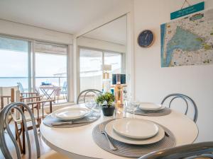 ein Esszimmer mit einem Tisch mit Stühlen und einer Uhr in der Unterkunft Apartment Aquitania-5 by Interhome in Arcachon + 19 Fotos