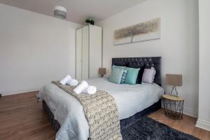 a bedroom with a large bed with blue pillows at Woodside Gardens Luxury Properties in London