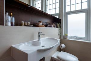 ein Bad mit einem Waschbecken, einem WC und einem Fenster in der Unterkunft Woodside Gardens Luxury Properties in London