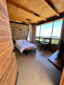1 dormitorio con 1 cama en una habitación con ventanas grandes en Villas MG, en Valle de Guadalupe
