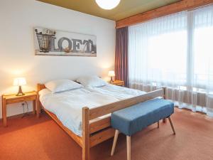 um quarto com uma cama com um banco azul e uma janela em Apartment Wildhorn 322 by Interhome em Les Collons
