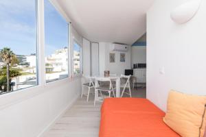 - un salon avec un canapé orange et une grande fenêtre dans l'établissement Apartamento Sol da Falésia, à Sesimbra