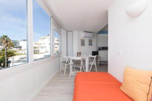 a living room with an orange couch and a large window at Apartamento Sol da Falésia in Sesimbra