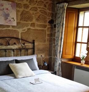 a bedroom with a bed and a stone wall at Casa Rural Vella da Rivera in O Sisto