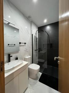 a white bathroom with a toilet and a sink at Santos House Praia in Praia