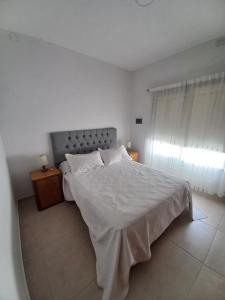 a white bedroom with a large bed and a window at La Juana in Almafuerte