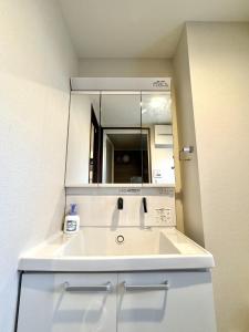 a bathroom with a white sink and a mirror at 最大5名宿泊 黒門市場徒歩1分 日本橋駅徒歩2分道顿堀難波心斎橋徒步7分金悦マンション in Osaka