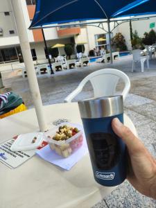 una mano sosteniendo una taza de café con un tazón de comida en Jardins das Thermas Caldas Novas perto do Clube Privê, en Caldas Novas