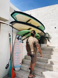 Un homme se tient sur les escaliers avec sa planche de surf dans l'établissement Turismo do Seculo, à Estoril