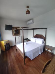 1 dormitorio con cama con dosel y suelo de madera en Pousada Solar da Inconfidencia - By UP Hotel - fácil acesso a Praça Tiradentes, en Ouro Preto