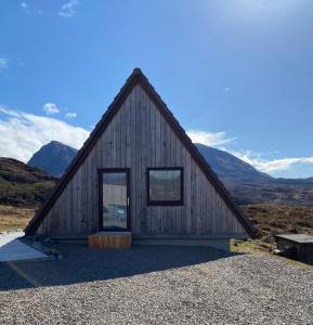 a small wooden house with mountains in the background at Kylesku Lodges in Kylestrome