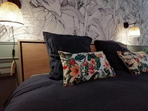 uma cama com duas almofadas e um papel de parede floral em Studio neuf-Wintzenheim-proche Colmar-Parking em Wintzenheim