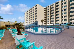 uma piscina em frente a um grande edifício com cadeiras azuis em Top of the Gulf 708 em Panama City Beach
