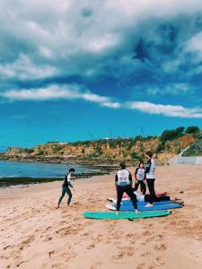 a group of people standing on surfboards on the beach at Turismo do Seculo in Estoril
