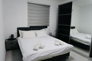 Schlafzimmer mit einem Bett mit weißer Bettwäsche und einem Spiegel in der Unterkunft אחוזת העמק סוויטות בפוריה in Poriyya