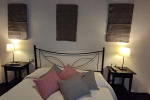 - une chambre avec un lit avec des oreillers et 2 lampes dans l'établissement Bosa Apartments Episcopio 1, à Bosa