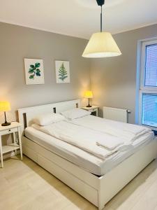 1 cama blanca en un dormitorio con 2 mesas y una lámpara en Apartament Aurora, Darmowy parking, Free parking, en Gdansk
